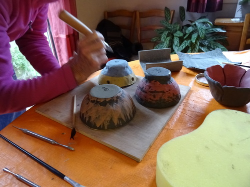 Saperlipoterie adulte décorant une poterie lors d'un atelier à domicile