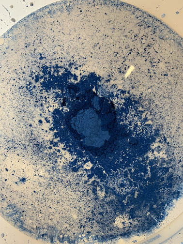 Saperlipoterie pigments bleux en poudre en train de se dissoudre dans un émail blanc liquide