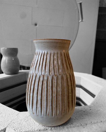 Saperlipoterie vase blanc posé sur le rebord du four de potier
